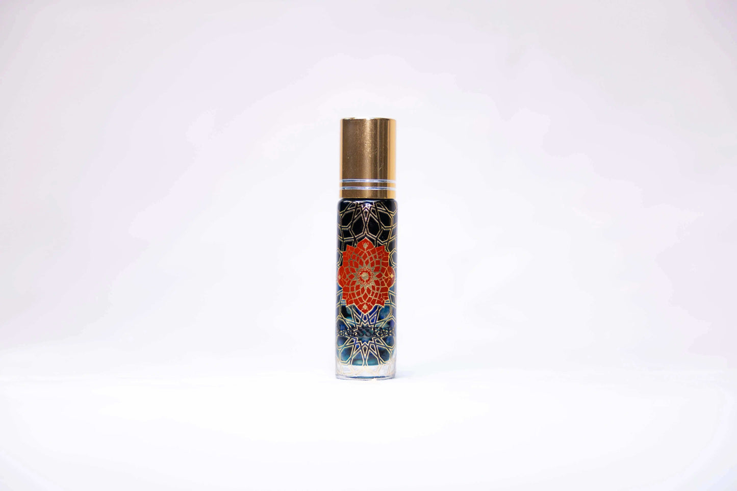 Blue Tansy and Lapis Lazuli Infusion Roll-On in clear glass bottle with gold cap and orange mandala flower on dark blue background