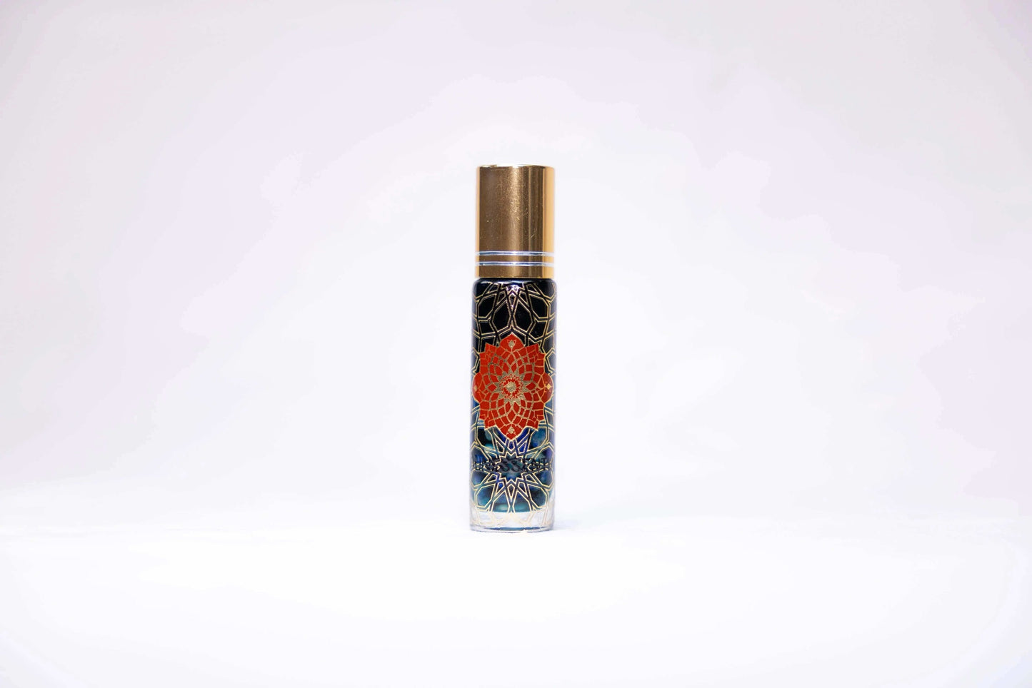 Blue Tansy and Lapis Lazuli Infusion Roll-On in clear glass bottle with gold cap and orange mandala flower on dark blue background