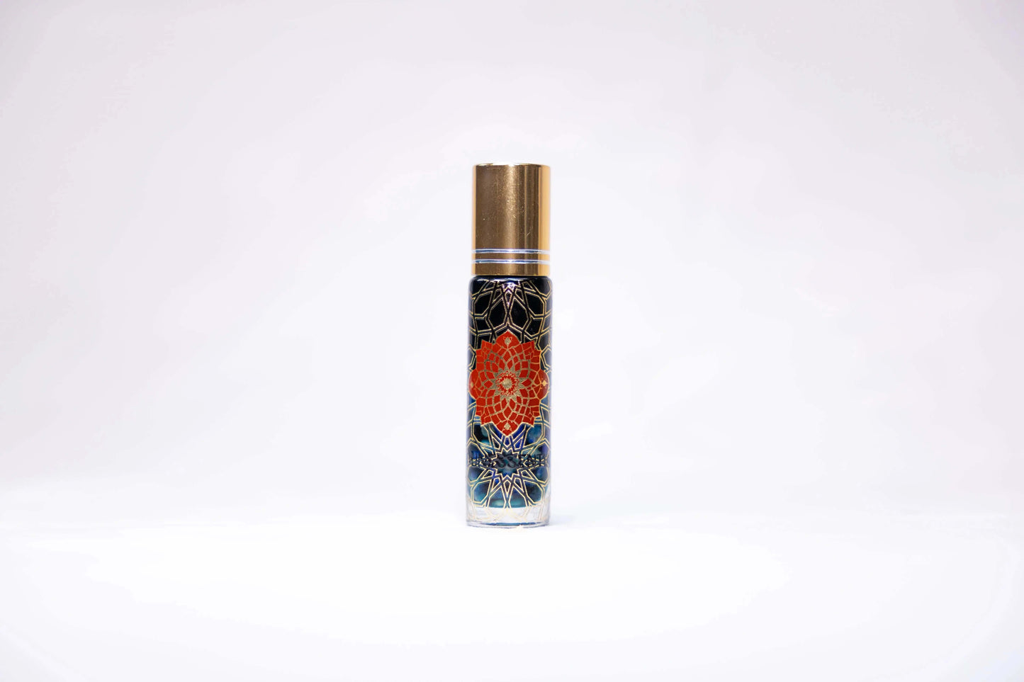 Blue Tansy and Lapis Lazuli Infusion Roll-On in clear glass bottle with gold cap and orange mandala flower on dark blue background