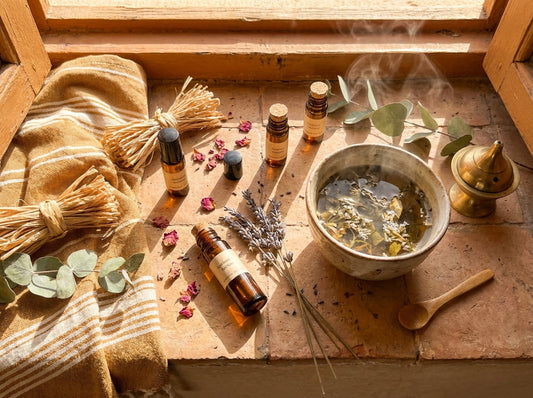Amber essential oil roll-on bottles and dried botanicals arranged on a sun-lit Moroccan terracotta windowsill during a peaceful morning ritual.